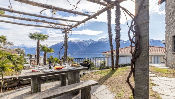 Una panca di pietra sotto una pergola con vista sulle montagne.