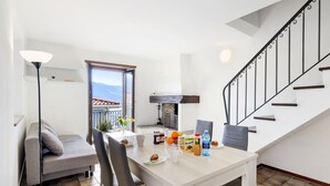 Zona pranzo con tavolo apparecchiato per due, divano e vista sull'esterno.