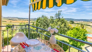 A balcony with a table set for dining, overlooking a scenic landscape. - Le Farsiche by Interhome (Castellina Marittima)