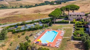 A pool area with lounge chairs and umbrellas, surrounded by greenery and hills. - Le Farsiche by Interhome (Castellina Marittima)