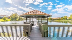 A gazebo with a wooden roof and railings, overlooking a calm lake with a clear sky. - Encantada Resort Townhome with Pool Near Disney (Kissimmee)
