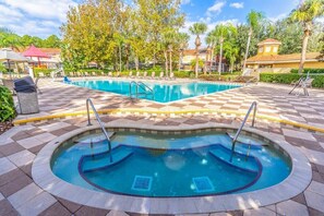 A swimming pool with a checkered tile pattern, surrounded by lounge chairs and palm trees.
