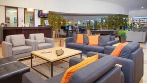 A modern lobby with sofas, a reception desk, and a pool area. - Encantada Resort Townhome with Pool Near Disney (Kissimmee)
