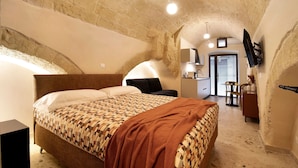 Ein Schlafzimmer mit einem Bett, einem Schreibtisch, einem Sessel und einem an der Wand befestigten Fernseher.