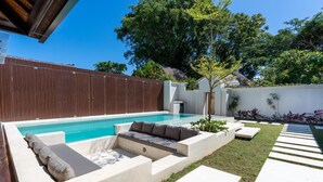 A modern outdoor pool area with a built-in seating area and a wooden fence. - Jimbaran Bay Villas (Kedonganan)