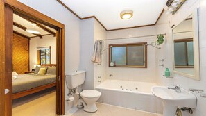 A bathroom with a bathtub, toilet, sink, and a window above the toilet. - The Treehouse on Hardys by HolidayCo. (KILLCARE)