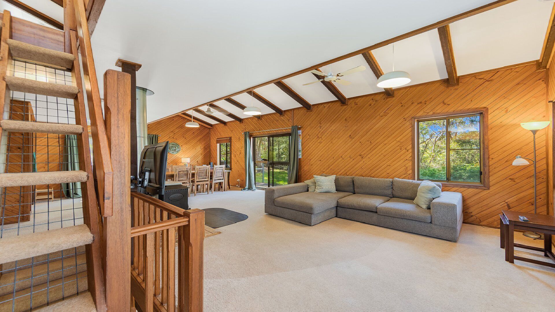 A spacious living area with a wooden ceiling, a sectional sofa, and a TV.