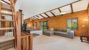 Un vaste espace de vie doté d’un plafond en bois, d’un canapé d’angle et d’un téléviseur.