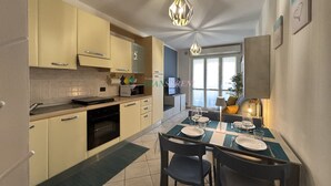 A modern kitchen with beige cabinets, a dining area with a table set for two, and a large window providing natural light. - 5 bed places with swimming pool in the area Coop (Toscana)