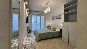 A modern bedroom with a bed, a chair, a radiator, a window, and a ceiling light fixture. - 5 bed places with swimming pool in the area Coop (Toscana)