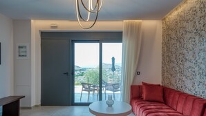 A modern living room with a red sofa, a round table, and a view through a glass door to the outdoors.