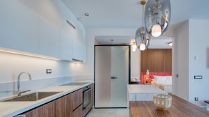 A modern kitchen with a built-in oven, a stainless steel sink, and wooden cabinets. There is a small island with a bowl on top.