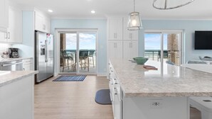 A modern kitchen with white cabinets, a stainless steel refrigerator, and a large island. - Beachfront Bliss: 3 Bdrm 1st Flr (Pawleys Island)