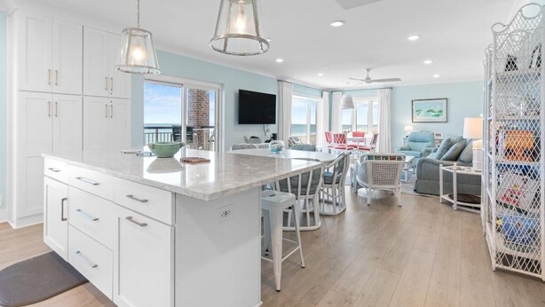 A spacious kitchen with white cabinets, a large island, and pendant lighting. - Beachfront Bliss: 3 Bdrm 1st Flr (Pawleys Island)