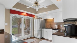 A modern kitchen with white cabinets, a stainless steel refrigerator, and a black coffee maker. - Perfectly Poised 2 Bedroom Oceanview 2nd Flr (Pawleys Island)