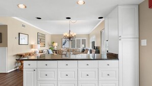 A spacious kitchen with a large island, white cabinetry, and a chandelier. - Perfectly Poised 2 Bedroom Oceanview 2nd Flr (Pawleys Island)