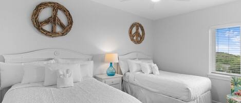 A bedroom with two beds, a ceiling fan, and a window with blinds.