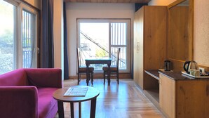 Una habitación moderna con suelo de madera, una mesa de comedor con sillas, un sofá rosa y una pequeña mesa con un periódico.