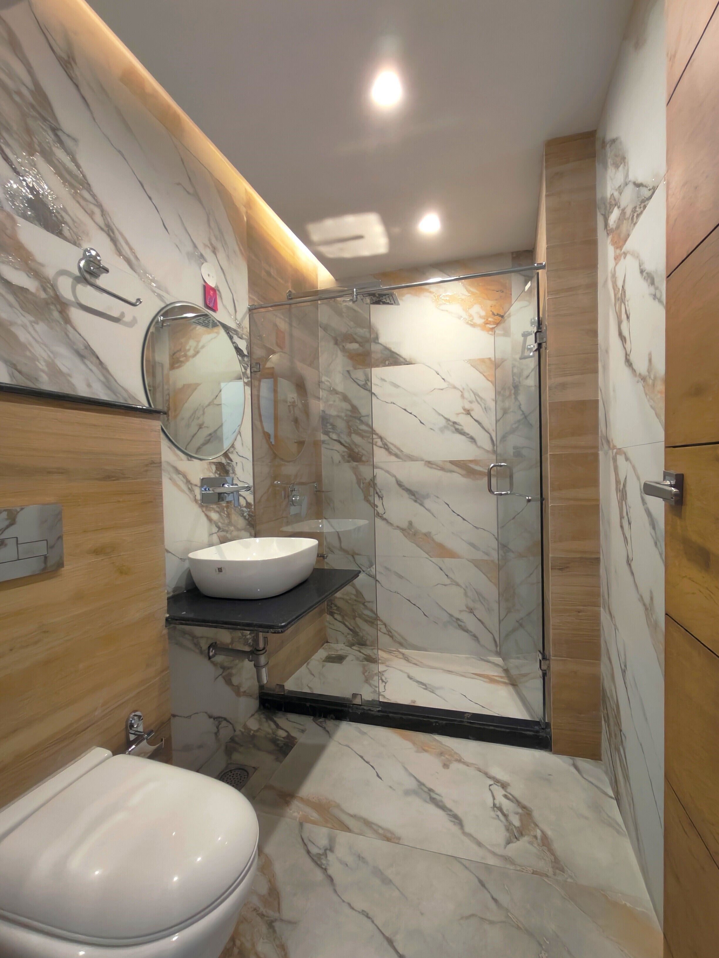 Ein Badezimmer mit Marmorwaschtisch, Waschbecken, Toilette und einer Duschkabine.