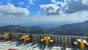 Una terraza con mobiliario exterior y vistas a un paisaje montañoso.