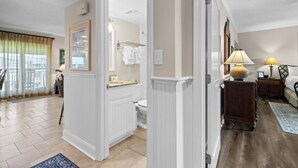 A modern bathroom with a toilet, sink, and towel rack. There is a mirror above the sink and a window with curtains.