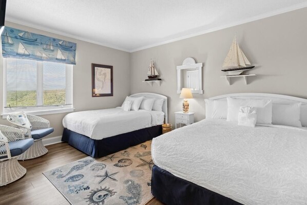 Un dormitorio con dos camas, una ventana con persianas, una silla, una mesita con lámpara y objetos decorativos en la pared.