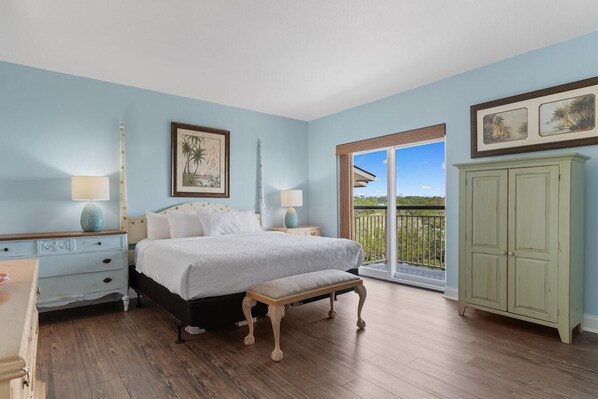 A bedroom with a bed, a bench, a dresser, and a view of the outdoors. - It's Time for the Beach: 3 Bdrm Oceanview 4th Flr (Pawleys Island)