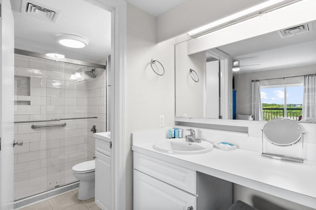 Ein modernes Badezimmer mit barrierefreier Dusche, Toilette und einem Waschtisch mit großem Spiegel und Waschbecken.