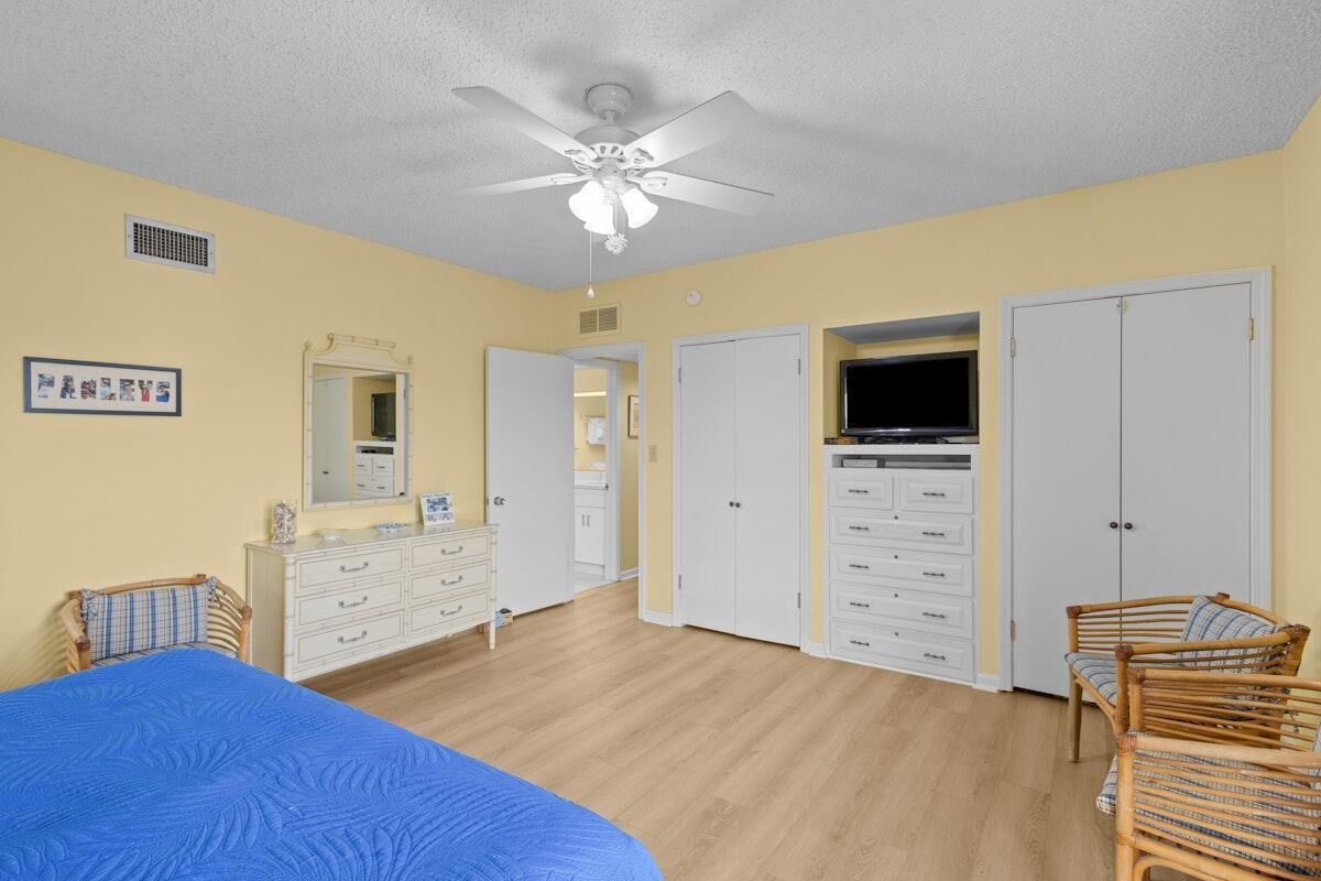 Een slaapkamer met een bed, een plafondventilator, een dressoir, een televisie en een kledingkast.