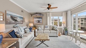 A living room with two patterned sofas, a wooden coffee table, and a ceiling fan. - 3rd Flr, 3 Bdrm Oceanview Condo Beach Oasis (Pawleys Island)