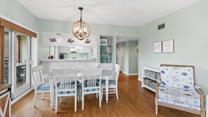 Un salon spacieux comprenant un coin repas, un lustre et un fauteuil à motifs.