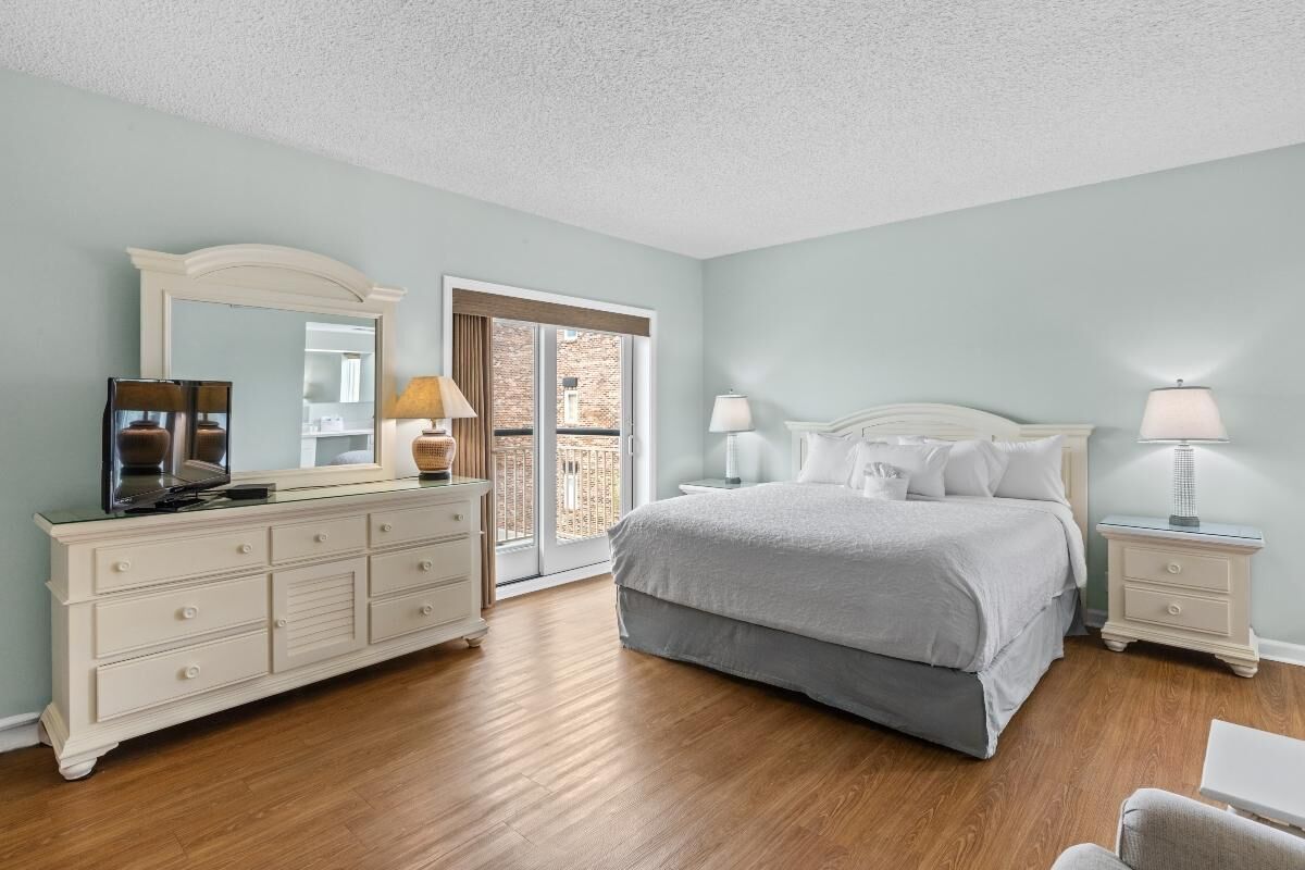 Een slaapkamer met een bed, een dressoir en nachtkastjes.