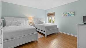 Une chambre avec deux lits, une commode, une table de chevet, une lampe et un téléviseur.