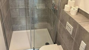 A small bathroom with a glass shower enclosure, a toilet, and a sink. - Spacious vacation apartment in Dresden Neustadt - your stylish temporary home (Dresden)