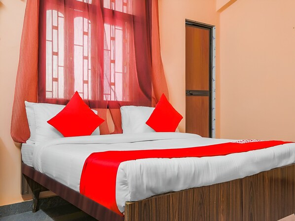 Una cama con ropa de cama blanca y detalles rojos, un cabecero de madera y un dosel rojo.