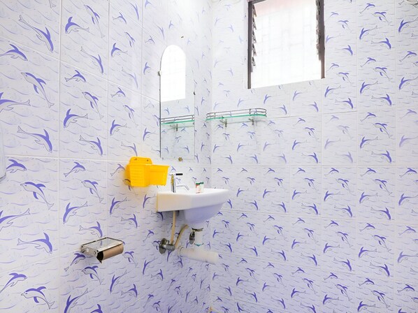 A bathroom with dolphin-patterned tiles, a white sink, a yellow basket, and a window. - Ma Micky Guest House (Colva)