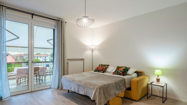 A bedroom with a bed, a bedside table, a lamp, and a view of the outside. - Attilia House - with WiFi and air conditioning (Sirmione)
