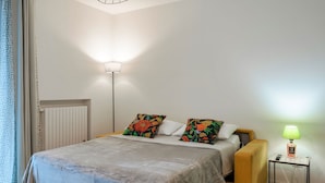 A bedroom with a bed, pillows, a bedside table with a lamp, and a radiator. - Attilia House - with WiFi and air conditioning (Sirmione)