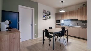 A modern kitchen with wooden cabinets, a built-in oven, and a microwave. There is a dining area with a table and chairs. - Attilia House - with WiFi and air conditioning (Sirmione)