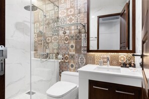 A bathroom with a shower, toilet, sink, and a mirror. - Arun Riverside Bangkok (Bangkok)