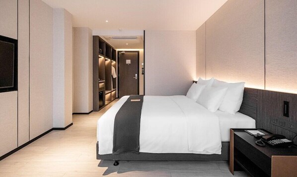 A modern hotel room with a large bed, a bedside table with a phone, and a walk-in closet. - Cascade Hotel Bangkok (Bangkok)