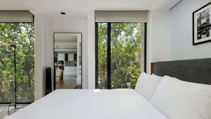 A modern bedroom with a large bed, a view of the outdoors through floor-to-ceiling windows, and a minimalist design. - Breathtaking loft in Roma Norte (Ciudad de México)