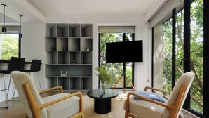 A modern living room with two wooden armchairs, a black coffee table, and a grey shelving unit. - Breathtaking loft in Roma Norte (Ciudad de México)