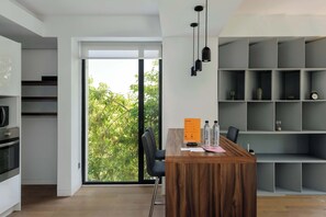 A modern kitchen with a wooden countertop, a built-in oven, and a sliding glass door leading to a balcony with greenery. - Breathtaking loft in Roma Norte (Ciudad de México)