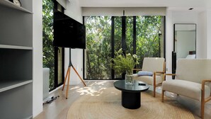 A modern living room with a large window, a flat-screen TV, a round coffee table, and a comfortable sofa. - Breathtaking loft in Roma Norte (Ciudad de México)