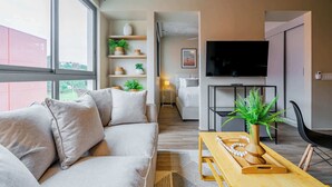 Ett modernt vardagsrum med en soffa, ett soffbord i trä och en tv. En trappa leder upp till ett annat rum.