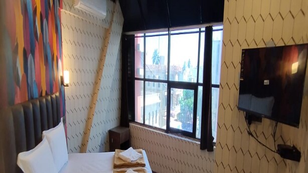 Ein Hotelzimmer mit Bett, Fernseher, Fenster und einer farbenfrohen Wand.