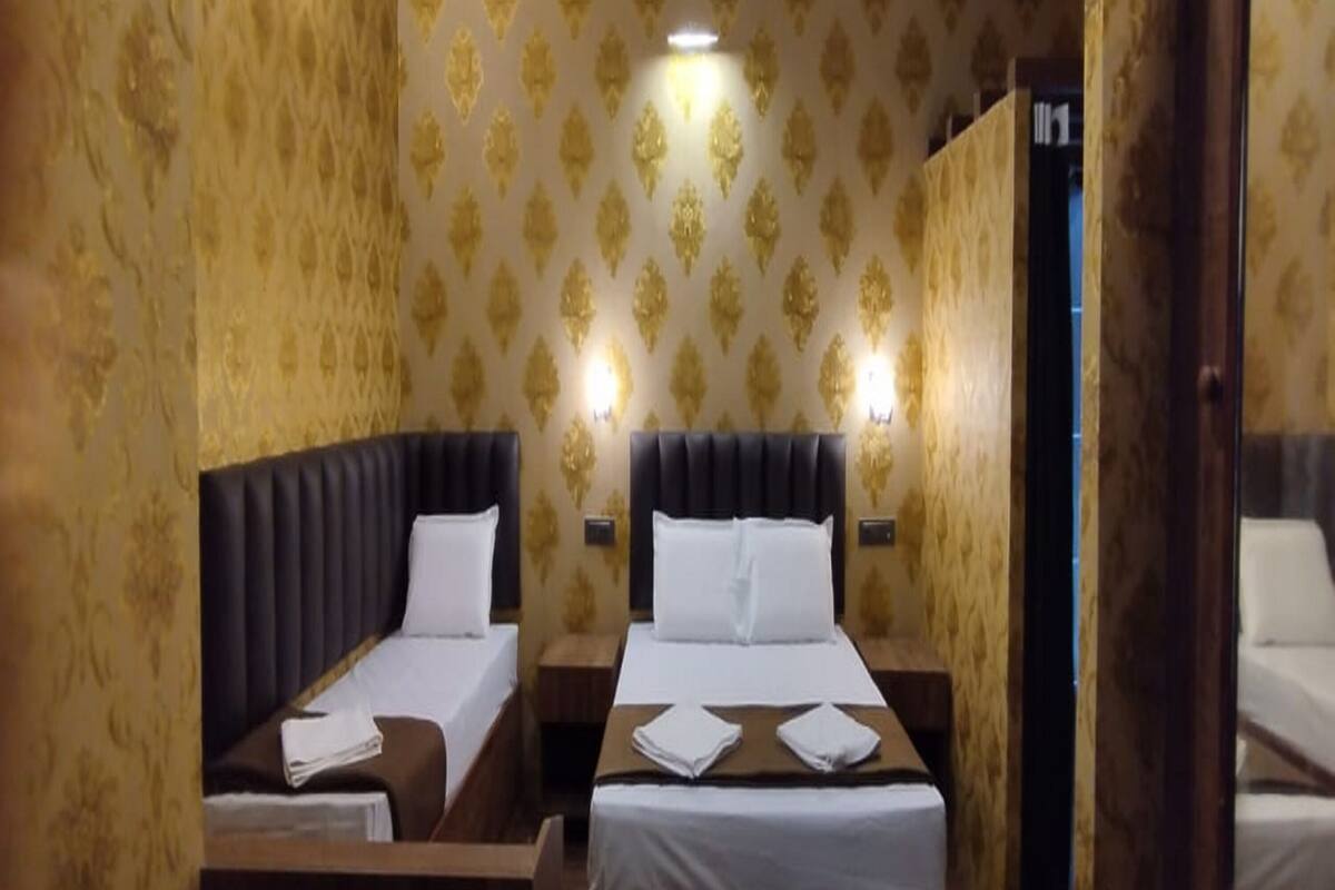 A hotel room with two beds, each with a headboard and white linens.