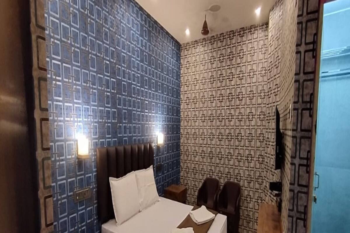 A bedroom with a bed, bedside tables, a dresser, and patterned walls.