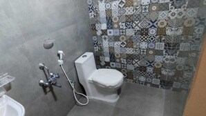 Ein kleines Badezimmer mit Toilette, Dusche und Waschbecken. Die Wände sind mit einem gemusterten Fliesenbild versehen.